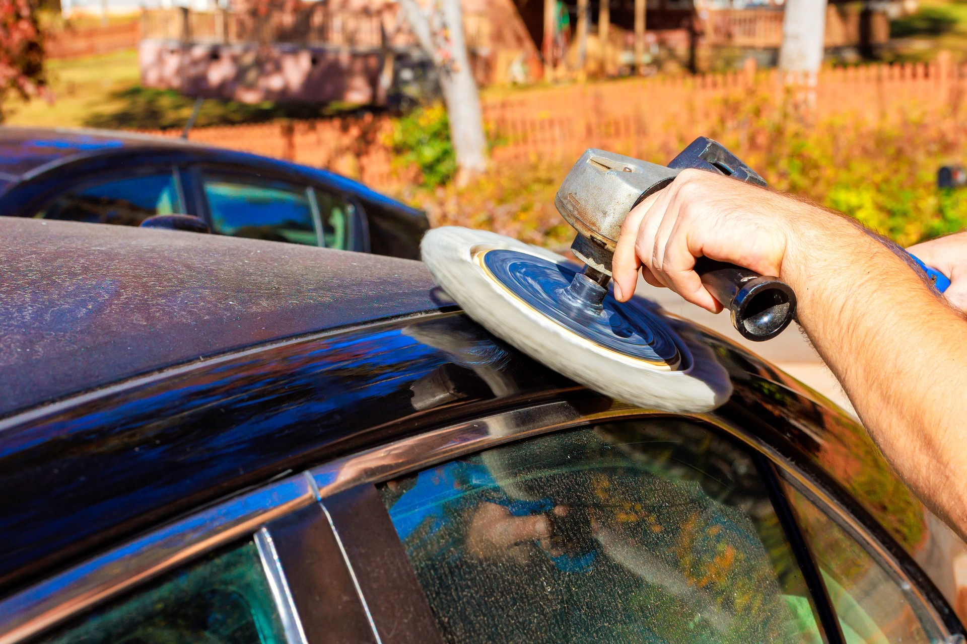 Car detailing process with buffing tool on a dusty vehicle in a sunny outdoor setting