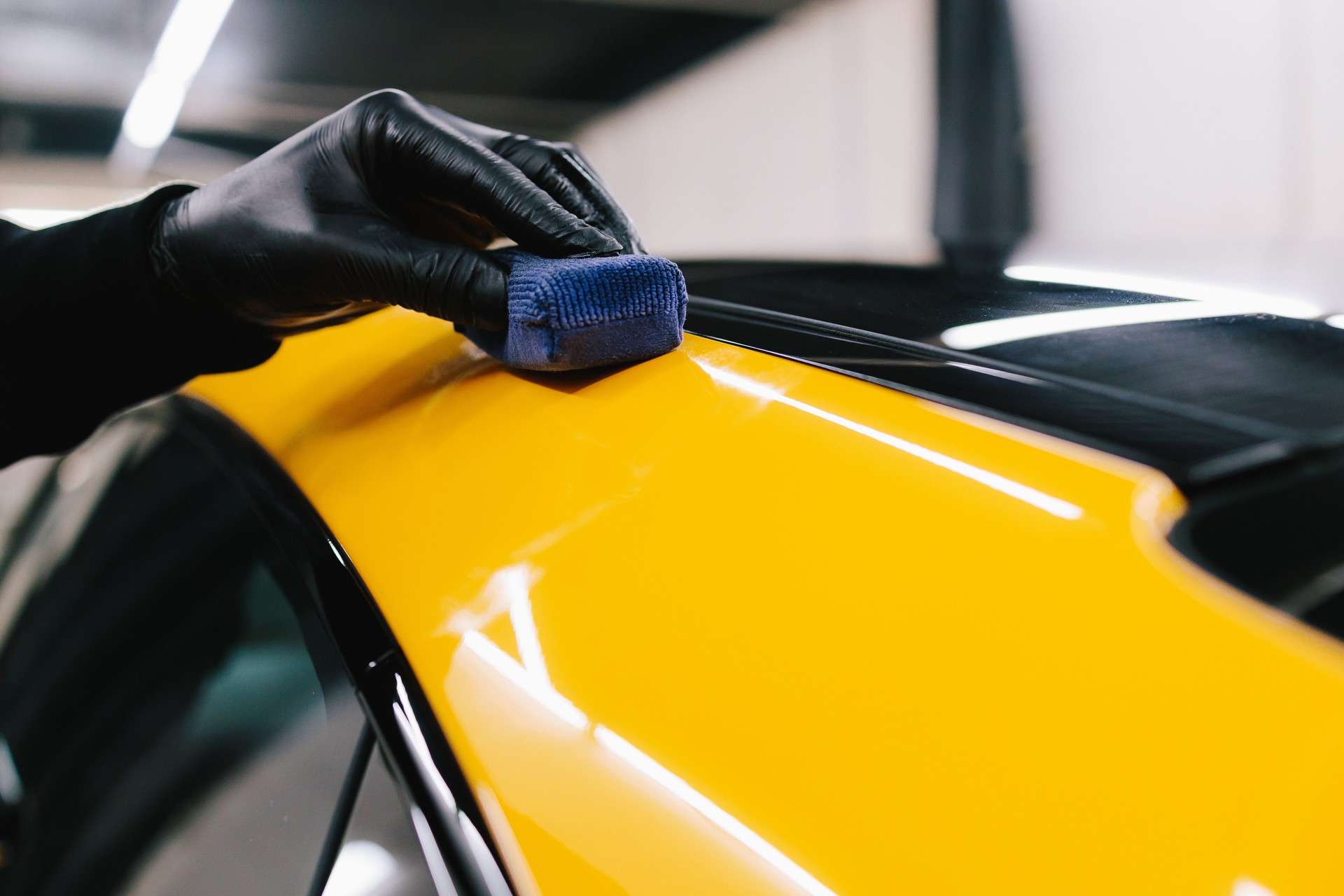 Process of applying a ceramic coating to the sports car surface for protection during detailing session at the service. Detailing ceramic polishing at the car service.